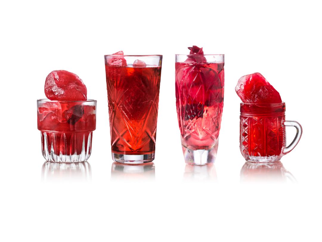 4 glasses of various shapes and sizes each filled with red, hibiscus iced tea