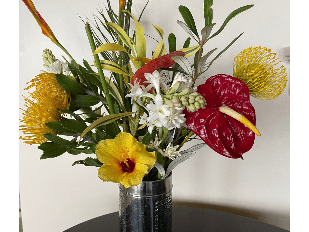 yellow, red, and white tropical floral arrangement in a silver can
