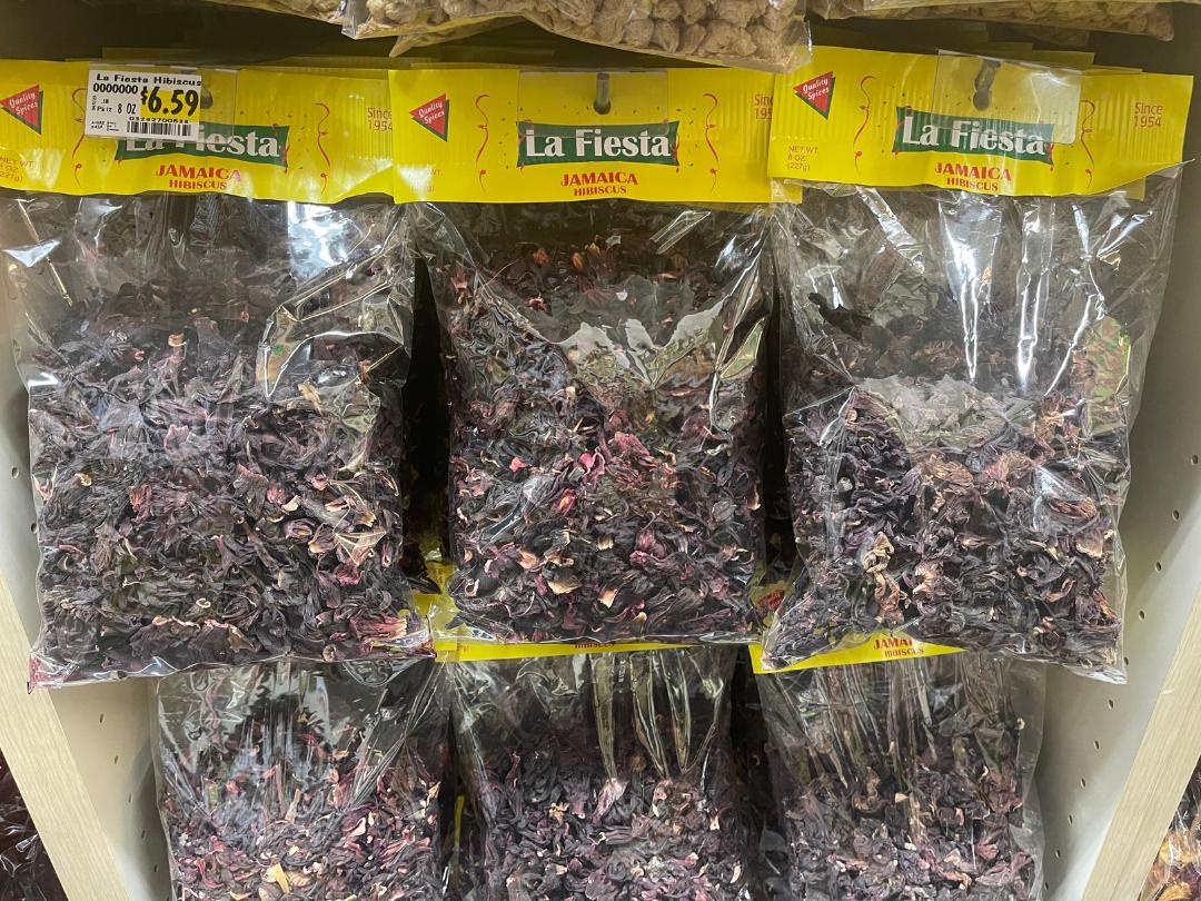 6 packaged bags of La Fiesta brand Jamaica dried hibiscus hanging on a store shelf