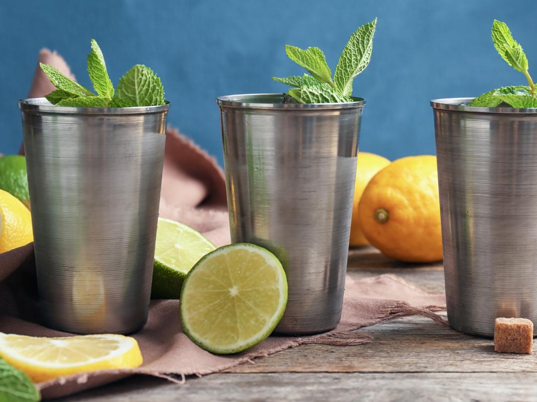 three frosty metal cocktail cups with fresh mint garnish