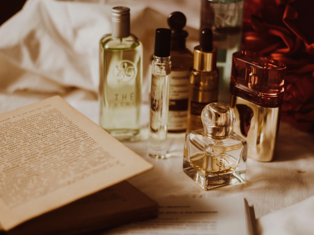 a collection of pretty perfume bottles next to a what seems to be an antique journal or book